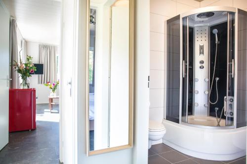 a glass shower in a room with a hallway at Groepshotel Leudal - Grote gezelschappen nabij Roermond aan de natuur in Haelen
