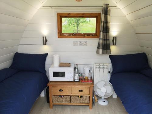 Habitación pequeña con 2 camas y microondas. en Craskie Glamping Pods, en Inverness