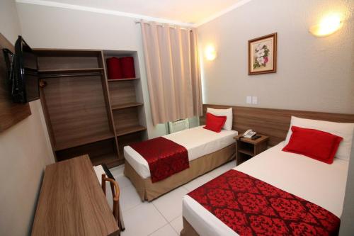 a hotel room with two beds with red pillows at Plaza Hotel São José dos Campos in São José dos Campos