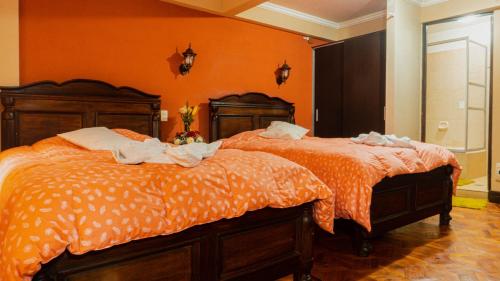two beds in a room with orange walls at Hostal La Magia de Uyuni in Uyuni