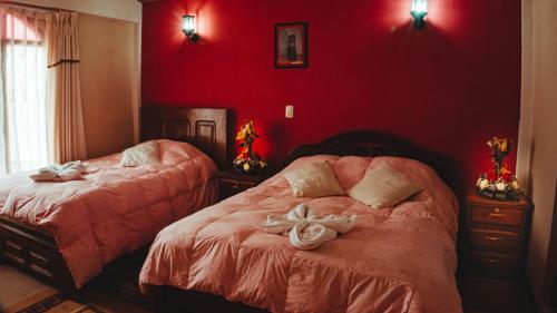 a bedroom with two beds with red walls at Hostal La Magia de Uyuni in Uyuni