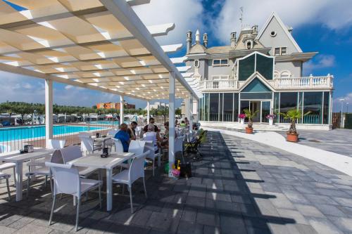 un patio con tavoli e sedie accanto alla piscina di Internazionale - Family Village a Sottomarina