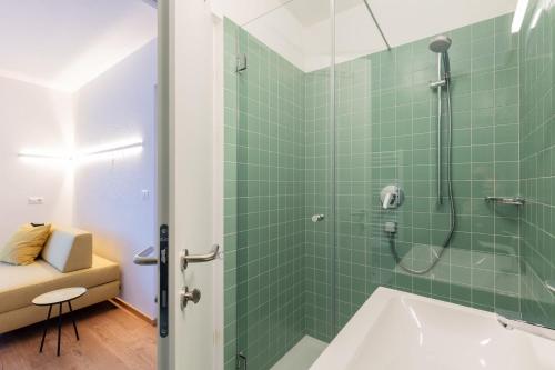 a bathroom with a shower with green tiles at Hus Appartement - Nr. 2 in Valdaora