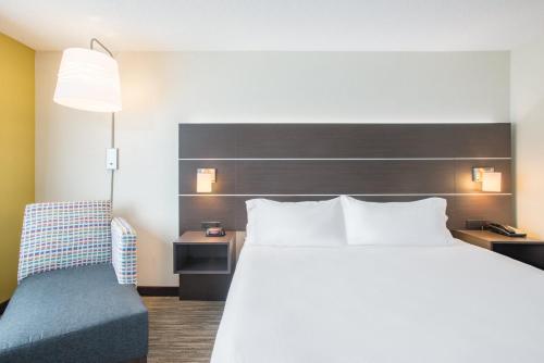 a bedroom with a large bed and a chair at Holiday Inn Express Hotel & Suites Boston - Marlboro by IHG in Hudson