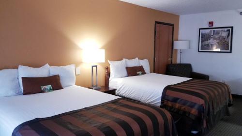 a hotel room with two beds and a chair at Wingate by Wyndham Airport - Rockville Road in Indianapolis