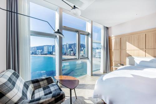 釜山にあるH Avenue Gwanganri Beachのベッドと大きな窓が備わるホテルルームです。