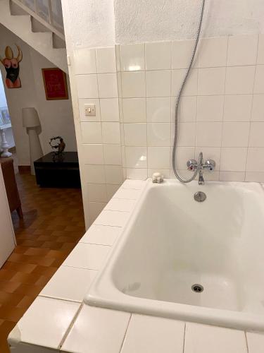 a white bath tub in a white tiled bathroom at La suite Galerie d'ART in Céret
