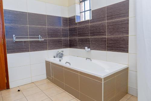 a bath tub in a bathroom with brown and white tiles at Orchid Homes, Gigiri in Nairobi