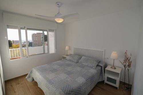 een witte slaapkamer met een bed en een raam bij New, Sunny, Near The Beach With Sea Views in Benalmádena