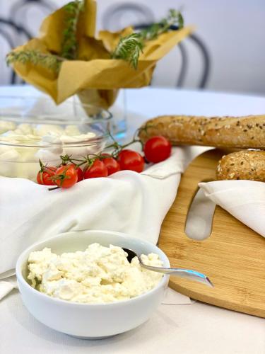 a bowl of cottage cheese on a cutting board with bread and tomatoes at Tursport in Taranto