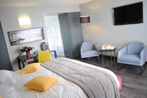 a bedroom with a bed and two chairs and a television at Hotel de L'Universite in Paris