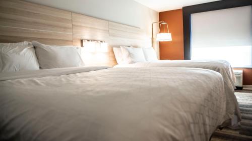 two beds in a hotel room with white sheets and pillows at Holiday Inn Express Hotel & Suites Sedalia by IHG in Sedalia