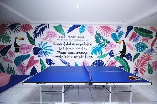 a ping pong table in front of a wall with a mural at d'Oasis Mountain Resort in Puncak
