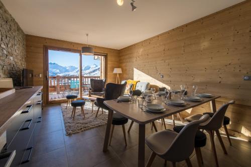 - une salle à manger avec une table, des chaises et des montagnes dans l'établissement ODYSSEE B201 - Magnifique Duplex sur les pistes, à La Toussuire