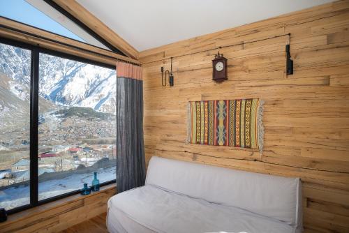 Kazbegi cabins في كازباجي: غرفة نوم بسرير ونافذة وساعة