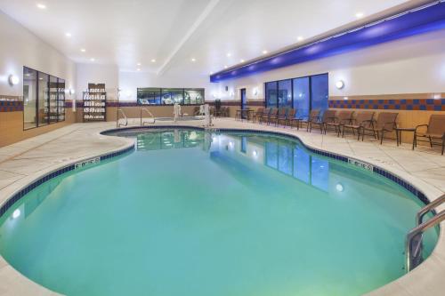 a swimming pool in a hotel lobby with chairs and tables at Holiday Inn Express and Suites Wheeling by IHG in Triadelphia