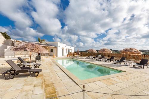 a swimming pool with chairs and umbrellas next to a house at B&B Mariano in Ceglie Messapica