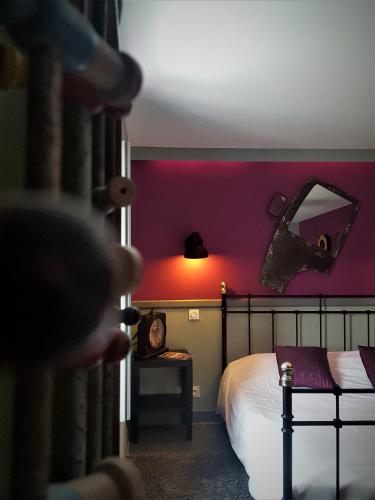 a room with a bed and a pink wall at Hotel restaurant La Pêcherie - Le manoir d'à coté - Les 5 ruches -Logis hôtels in Courseulles-sur-Mer