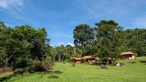 a field with a house and some trees and grass at Chalés Das Estrelas in Visconde De Maua
