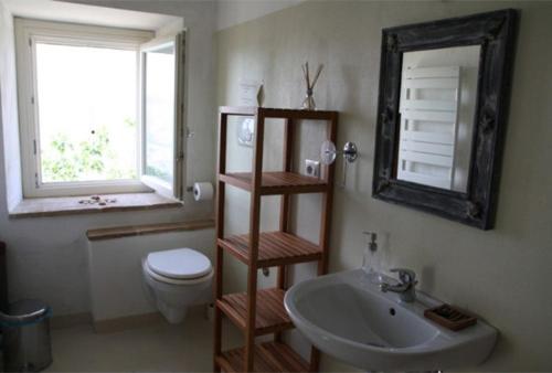 a bathroom with a sink and a toilet and a mirror at Angeli di Montefiore in Montefiore dellʼAso