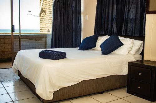 a bed with two blue pillows on top of it at Seven Seas SA in Amanzimtoti