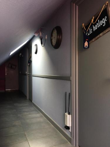 a hallway with a clock on the wall next to a hallway sidx sidx at Hotel restaurant La Pêcherie - Le manoir d'à coté - Les 5 ruches -Logis hôtels in Courseulles-sur-Mer