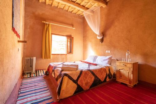 Schlafzimmer mit einem Bett und einem Fenster in der Unterkunft Riad Kasbah des Roches in Akhendachou nʼAït Ouffi