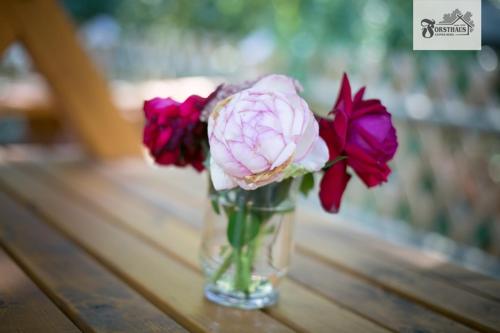 a glass vase filled with flowers on a table at Forsthaus Leiner Berg in Dessau