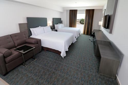 a hotel room with two beds and a couch at Holiday Inn Express Hotel & Suites Hermosillo by IHG in Hermosillo