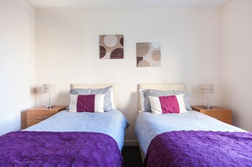 two beds in a bedroom with purple sheets at City View in Aberdeen