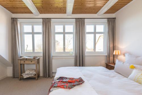 a bedroom with a bed and two windows at Ferienhof Kähler in Fehmarn