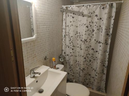 y baño con aseo y cortina de ducha. en Habitación JC en Madrid