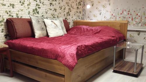 a wooden bed with a red comforter and pillows at Small and cozy studio apartment in Riga