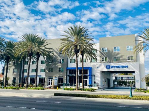 a building with palm trees in front of a street at Wyndham Anaheim in Anaheim