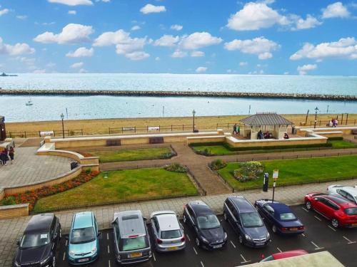 a parking lot with cars parked in front of the water at Aqua Bay Guest House in Herne Bay