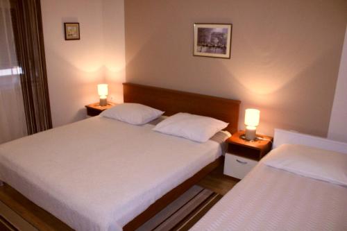 two beds in a room with two lamps on tables at Apartments Silvana sunset view in Zadar