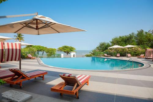 - une piscine avec 2 chaises et un parasol dans l'établissement Radisson Blu Okoume Palace Hotel, Libreville, à Libreville