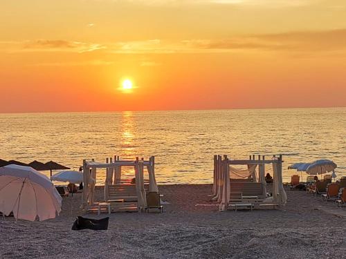 a beach with chairs and umbrellas at sunset at Hotel Porto Badisco in Porto Badisco