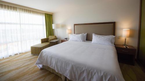 a hotel room with a large white bed and a chair at Holiday Inn Express and Suites Celaya by IHG in Celaya