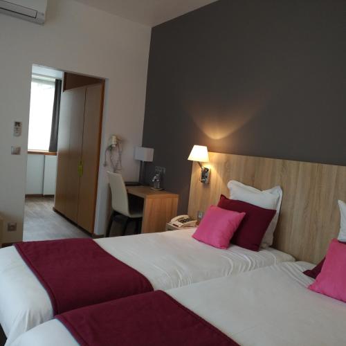 a hotel room with two beds with pink pillows at Logis Hôtel Notre-Dame - restaurant ouvert midi et soir sauf dimanche soir in Danne-et-Quatre-Vents