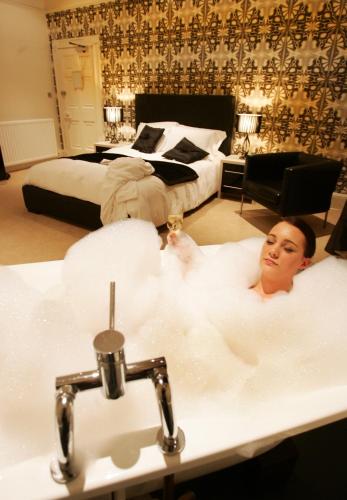 a man sitting in a bath tub in a bedroom at Boutique 25 in Skipton