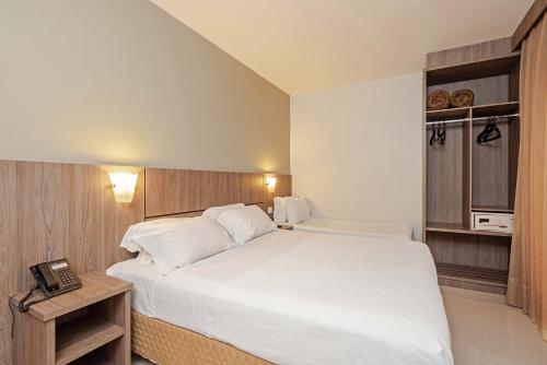 a hotel room with a bed and a telephone at Slim Curitiba Av das Torres in Curitiba