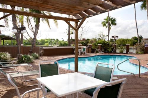 un patio con mesa, sillas y piscina en Holiday Inn Express Hotel and Suites Brownsville, an IHG Hotel en Brownsville