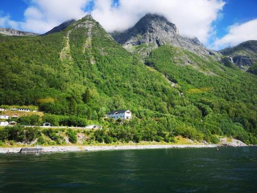 una casa sul fianco di una montagna vicino all'acqua di Iris Vedal a Nauste
