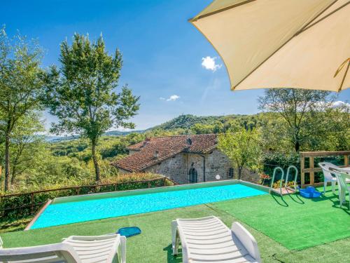 a pool with chairs and an umbrella and a house at Holiday Home Casale Labbia by Interhome in Barberino di Mugello