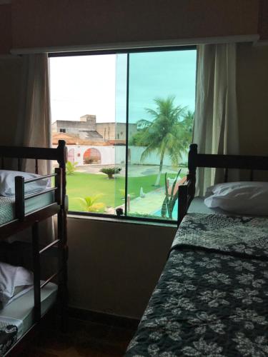 um quarto com 2 beliches e uma grande janela em Pousada La Maison em Iguaba Grande