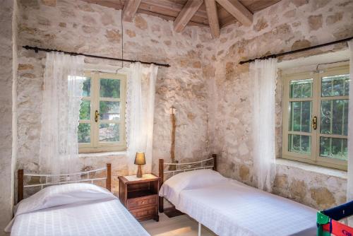 two beds in a room with stone walls and windows at Jianni's Villa - Stone Villa in the Greenery!! in Vasilikos
