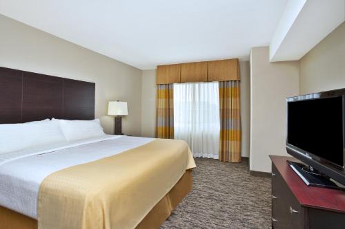 a hotel room with a bed and a flat screen tv at Holiday Inn & Suites Green Bay Stadium by IHG in Green Bay