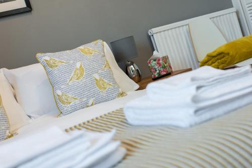 a bed with a pile of white sheets and a pillow at The Westfield in Edinburgh