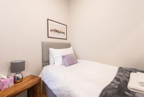 a small bedroom with a white bed and a wooden table at The Westfield in Edinburgh